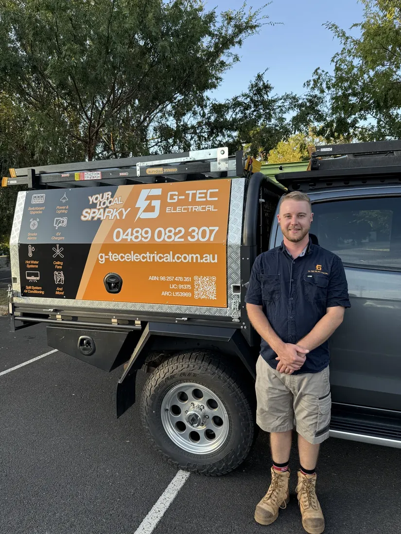 Glenn, who owns G-TEC Electrical and does the work, in a navy work shirt beside his ute, its toolbox canopy wrapped in the brand's orange and navy.