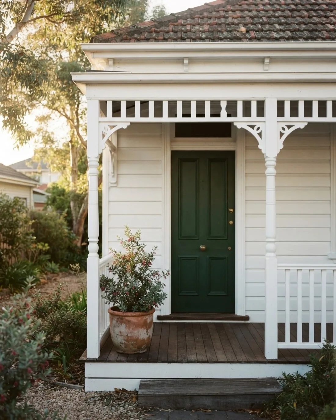 A freshly painted weatherboard verandah with a green front door in late light