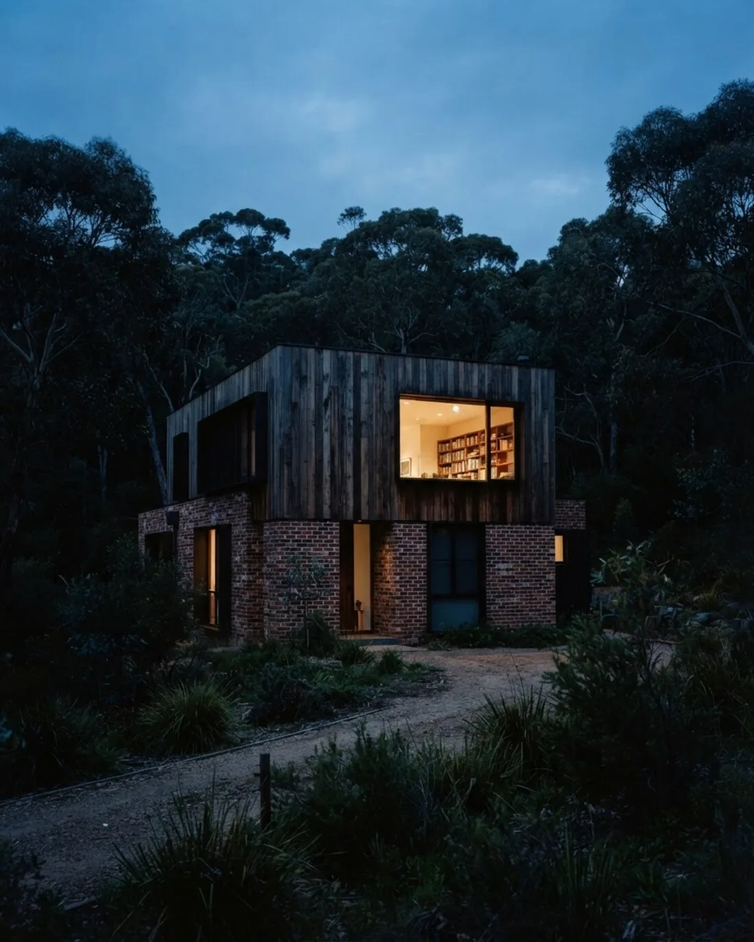 A single architect-designed house at dusk with one warm lit window