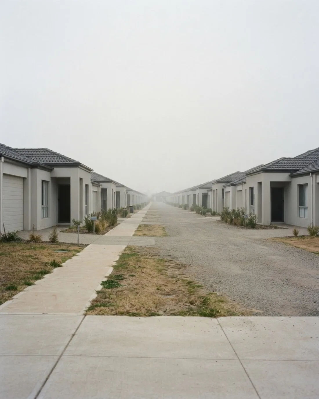 A street of near-identical project homes receding into haze