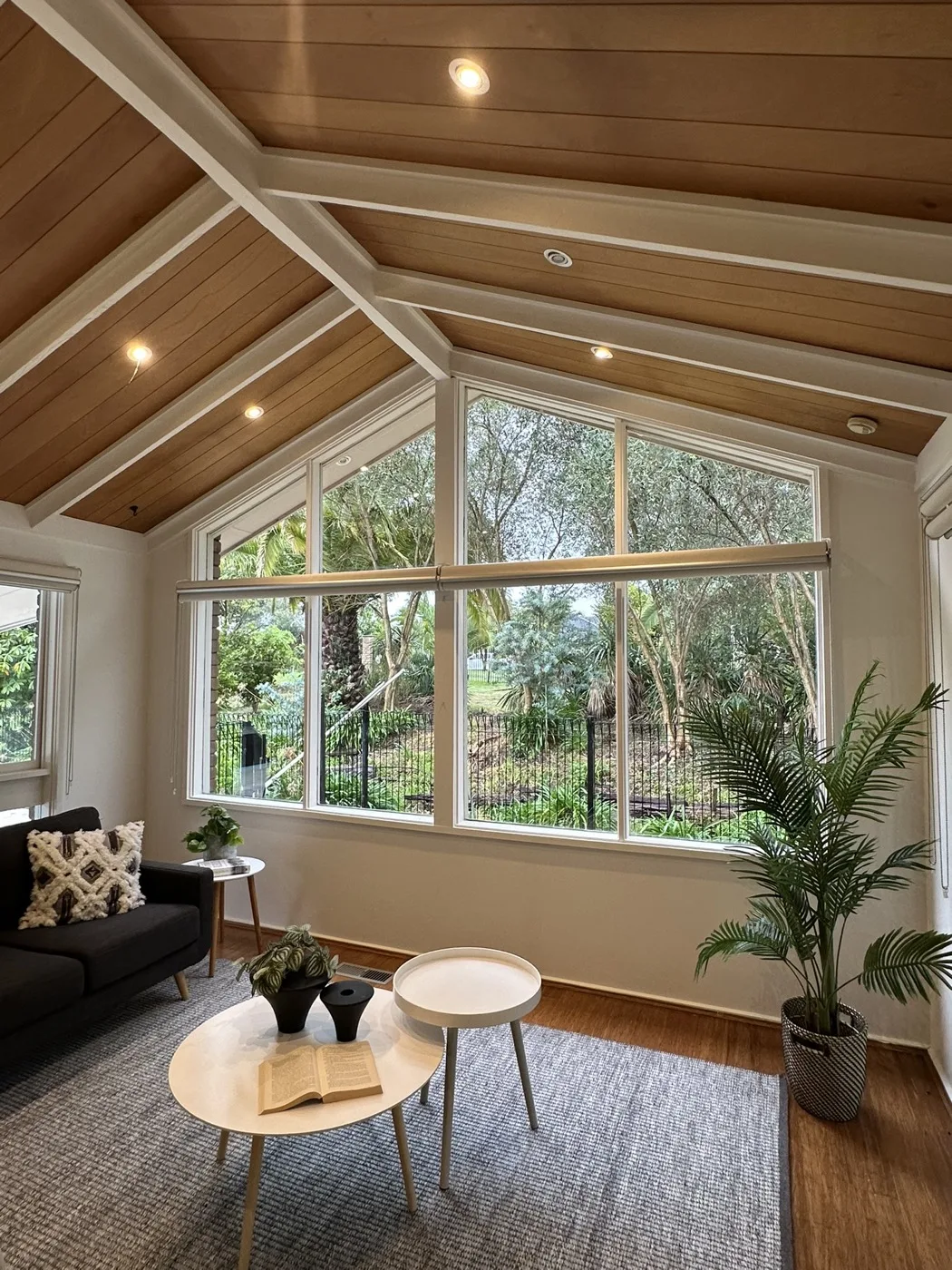 Roller blinds fitted in a timber-ceilinged sunroom looking onto a garden