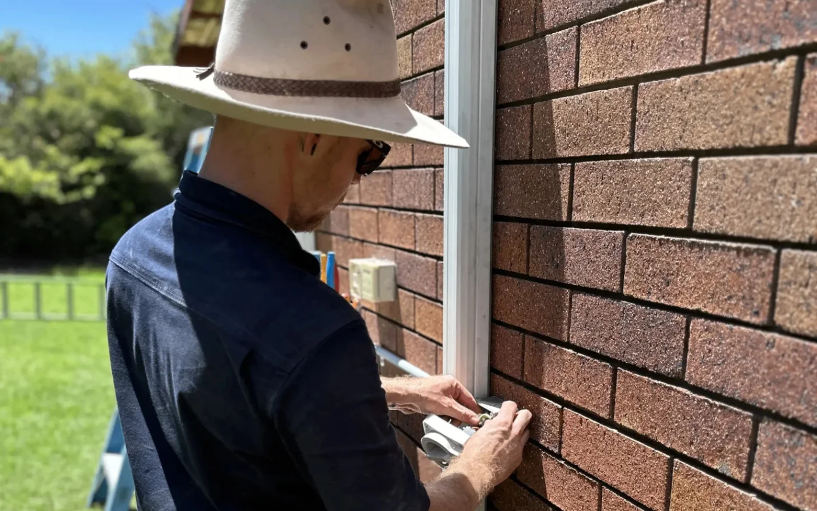 Glenn testing a meter box on a brick wall in Toowoomba