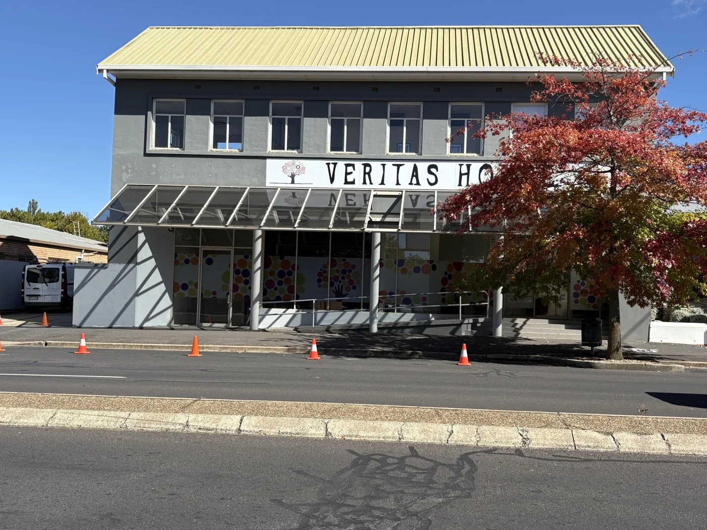 A finished commercial repaint in Orange, fresh grey render under a gold roof